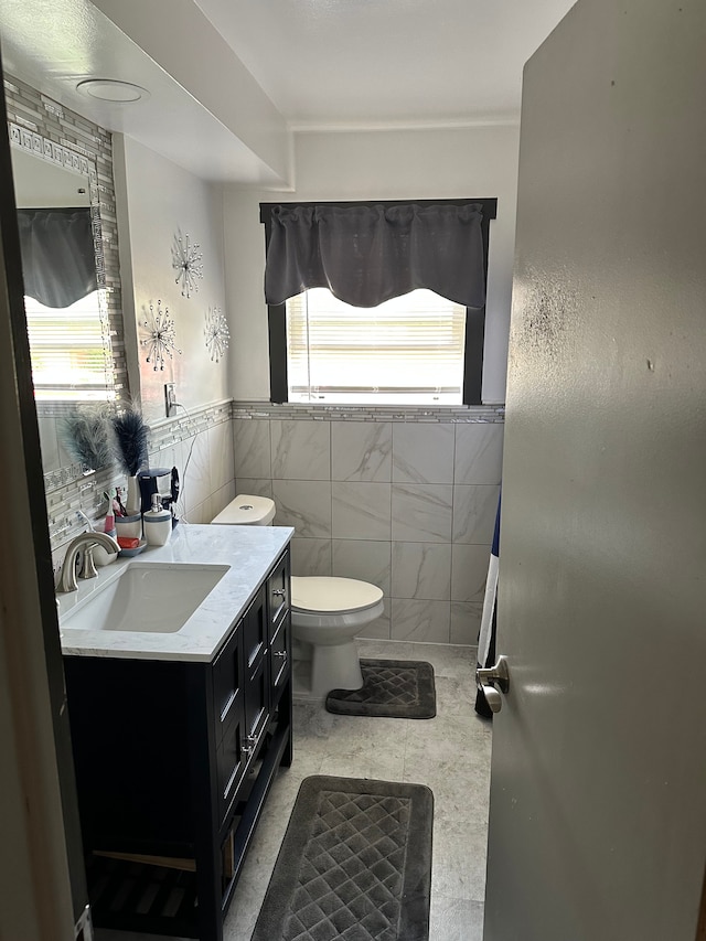 bathroom with tile patterned flooring, vanity, toilet, and tile walls