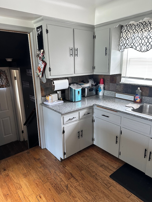 kitchen with tasteful backsplash, sink, white cabinets, and dark wood-type flooring