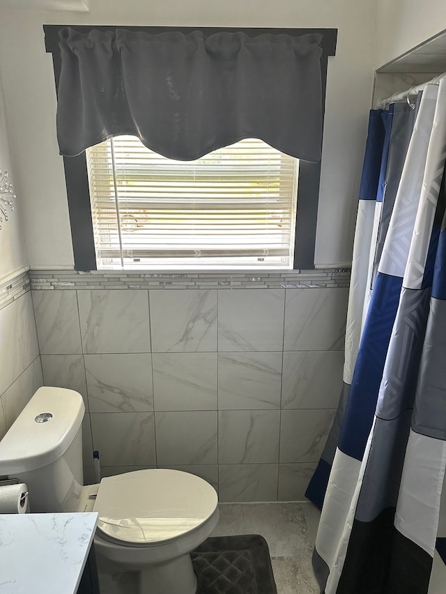 bathroom with vanity, tile walls, and toilet