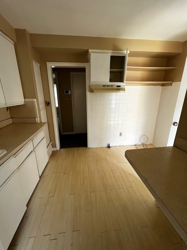 kitchen with white cabinets, light wood-type flooring, and tasteful backsplash