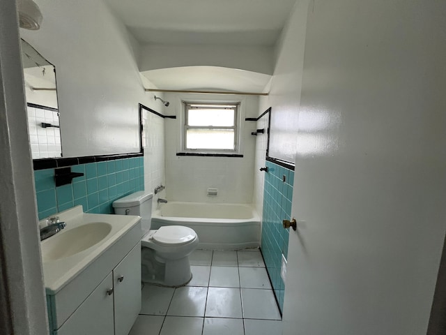 full bathroom featuring vanity, tiled shower / bath, tile patterned flooring, toilet, and tile walls