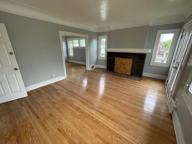 unfurnished living room with light hardwood / wood-style flooring, a brick fireplace, and a healthy amount of sunlight