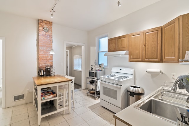 kitchen featuring light tile patterned floors, track lighting, white gas range, and sink