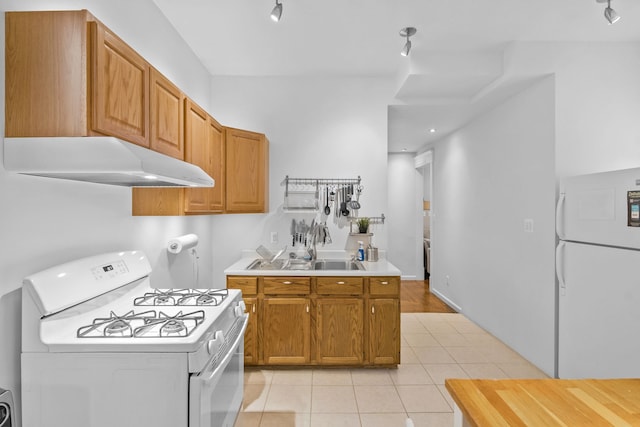 kitchen featuring white appliances, rail lighting, and light tile patterned floors