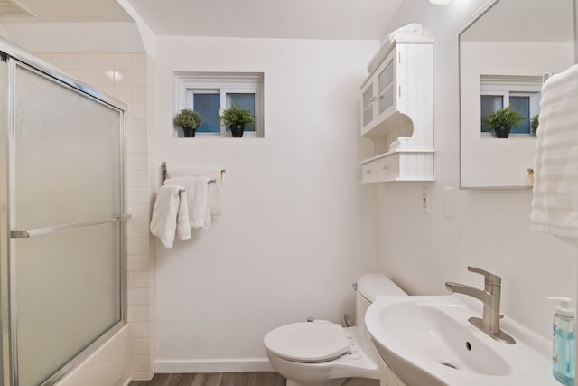 full bathroom featuring hardwood / wood-style flooring, toilet, bath / shower combo with glass door, and sink