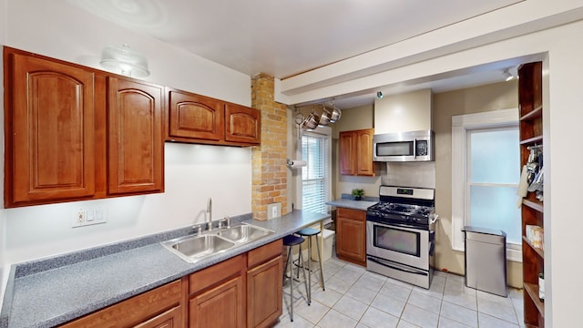 kitchen with a kitchen breakfast bar, sink, light tile patterned floors, and stainless steel appliances