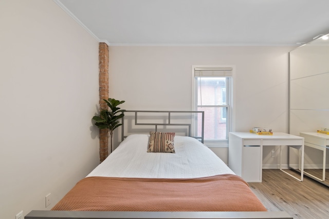 bedroom with light wood-type flooring and crown molding