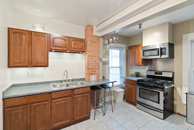 kitchen featuring a breakfast bar area, sink, light tile patterned floors, and appliances with stainless steel finishes