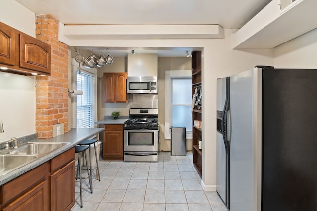 kitchen featuring appliances with stainless steel finishes, light tile patterned floors, a breakfast bar area, and sink