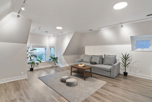 living room with wood-type flooring, track lighting, and vaulted ceiling