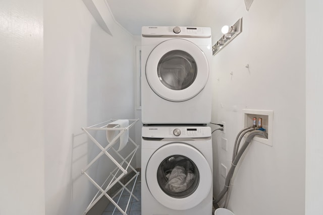 clothes washing area featuring tile patterned floors and stacked washing maching and dryer