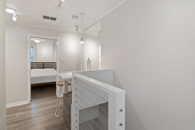 interior space with wood-type flooring, track lighting, and ornamental molding