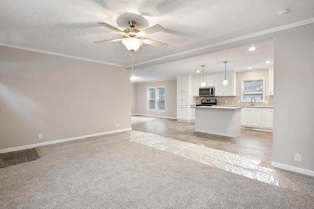 unfurnished living room featuring sink, ceiling fan, crown molding, and a textured ceiling