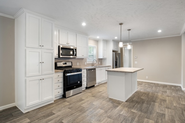 kitchen featuring sink, stainless steel appliances, light hardwood / wood-style flooring, pendant lighting, and white cabinets