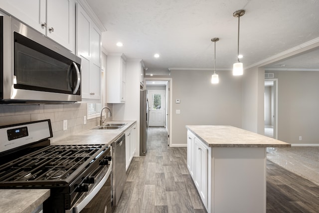 kitchen featuring white cabinetry, sink, stainless steel appliances, wood-type flooring, and a kitchen island