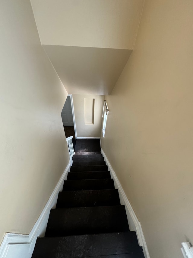 stairway featuring hardwood / wood-style flooring and lofted ceiling