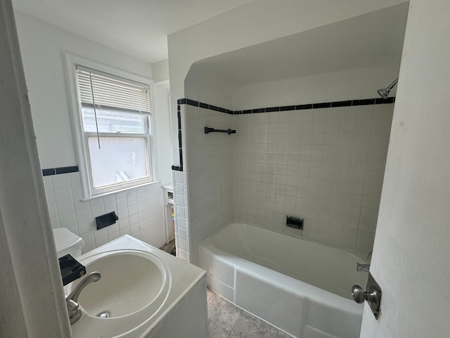 bathroom featuring tile patterned floors, sink, tiled shower / bath combo, and tile walls