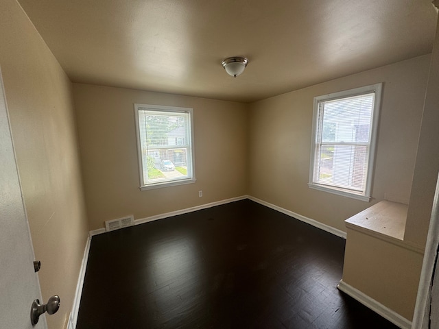 unfurnished room with dark hardwood / wood-style flooring and a wealth of natural light