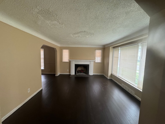 unfurnished living room featuring dark hardwood / wood-style flooring and a textured ceiling