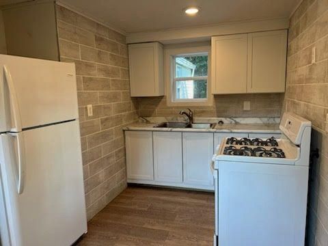 kitchen featuring white cabinetry, sink, hardwood / wood-style floors, and white appliances