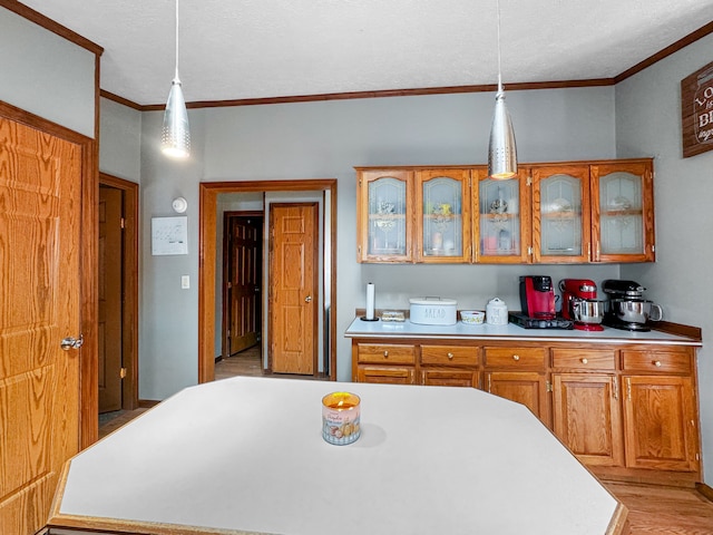 kitchen with ornamental molding, hanging light fixtures, and light hardwood / wood-style floors