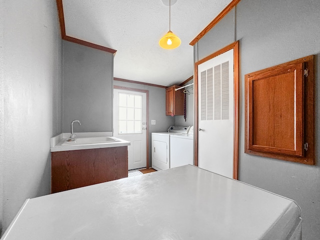 washroom with washer and clothes dryer, cabinets, crown molding, sink, and a textured ceiling