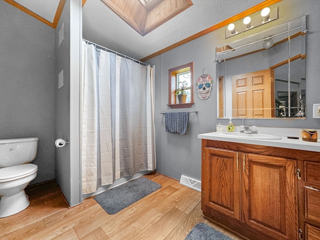 bathroom with ornamental molding, vanity, a textured ceiling, hardwood / wood-style floors, and toilet