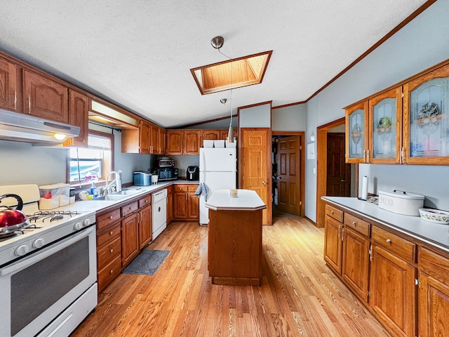 kitchen with decorative light fixtures, white appliances, a center island, and light hardwood / wood-style floors