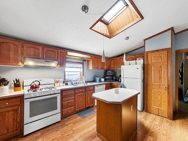 kitchen featuring white appliances, lofted ceiling with skylight, a kitchen island, decorative light fixtures, and light hardwood / wood-style floors