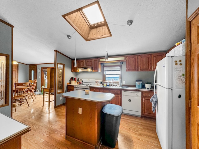 kitchen featuring light wood-type flooring, a skylight, white appliances, a kitchen island, and hanging light fixtures