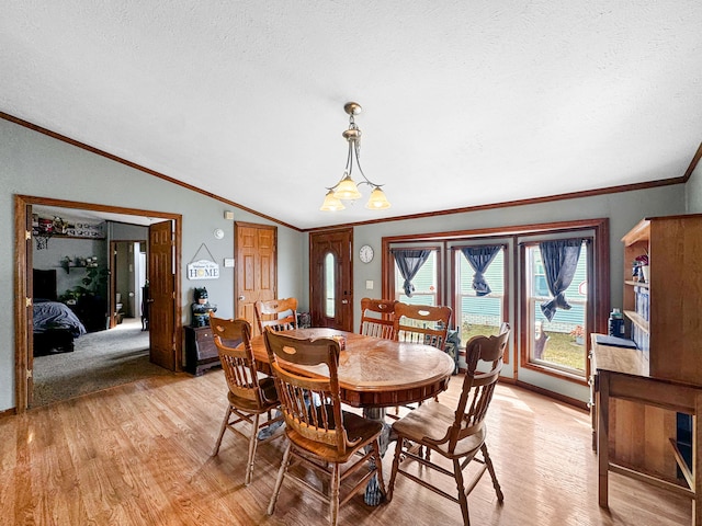 dining area featuring lofted ceiling, light hardwood / wood-style flooring, ornamental molding, a textured ceiling, and a notable chandelier