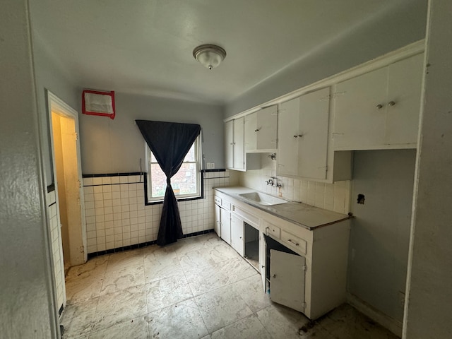 kitchen with white cabinets, tile walls, and sink