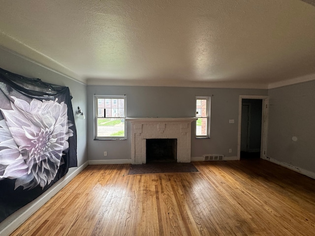 unfurnished living room featuring a textured ceiling, light hardwood / wood-style flooring, and a healthy amount of sunlight