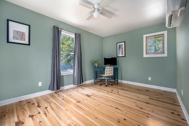 unfurnished office featuring ceiling fan, a wall mounted AC, and light hardwood / wood-style flooring