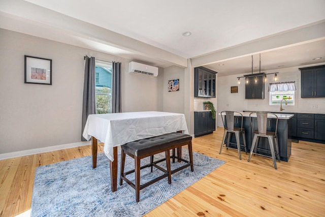 dining space with light wood-type flooring, a wall mounted AC, and sink