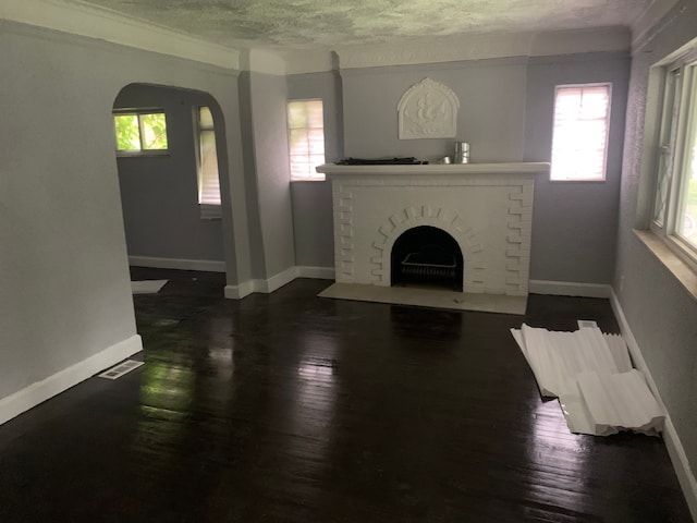 living room with a fireplace, dark wood-type flooring, a textured ceiling, and ornamental molding