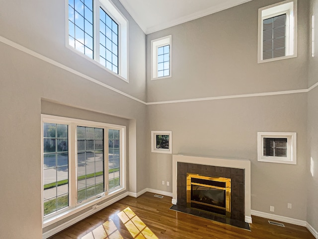 unfurnished living room with plenty of natural light, dark hardwood / wood-style flooring, and a tile fireplace