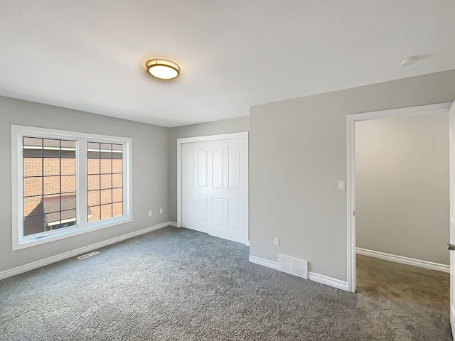 unfurnished bedroom featuring dark colored carpet and a closet