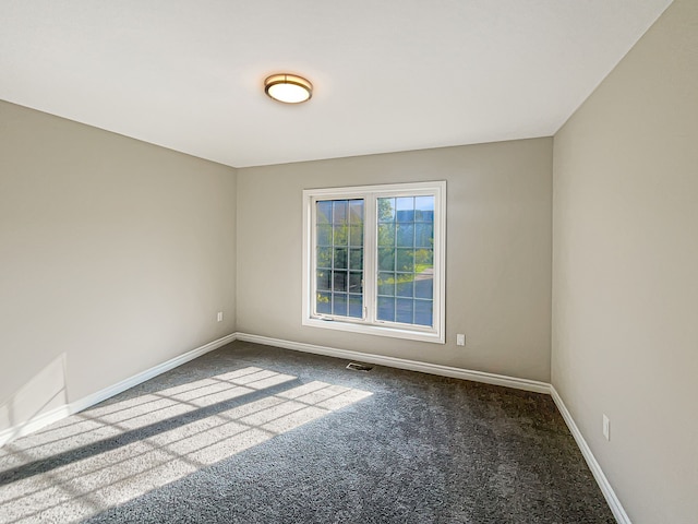 unfurnished room featuring dark carpet