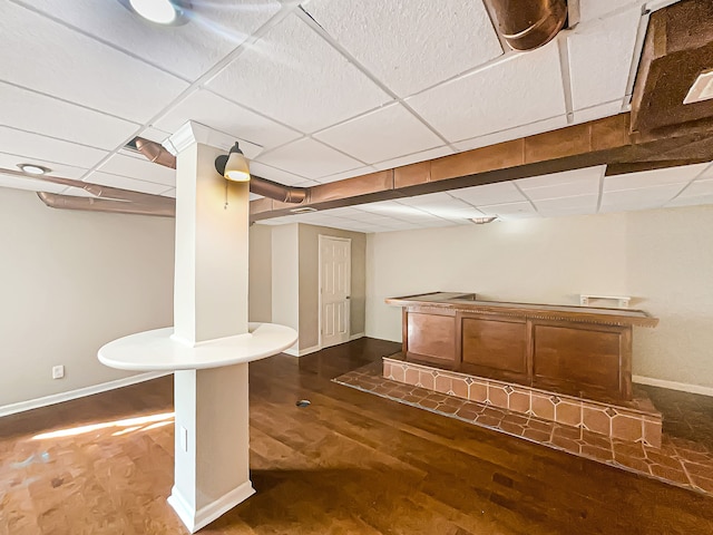 bar with a drop ceiling and dark wood-type flooring