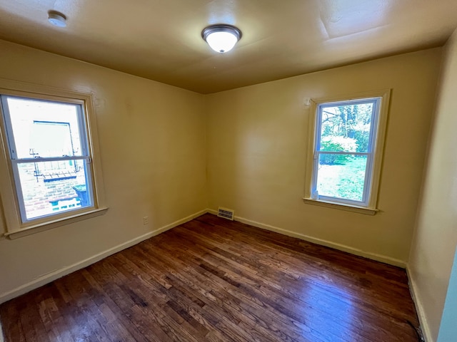 empty room with dark wood-type flooring and a healthy amount of sunlight