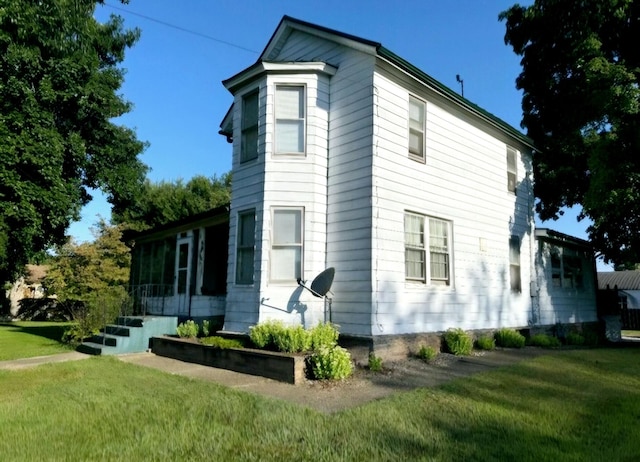 view of side of property with a sunroom and a yard