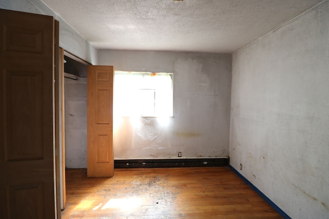 unfurnished bedroom featuring dark hardwood / wood-style floors, a textured ceiling, and a closet