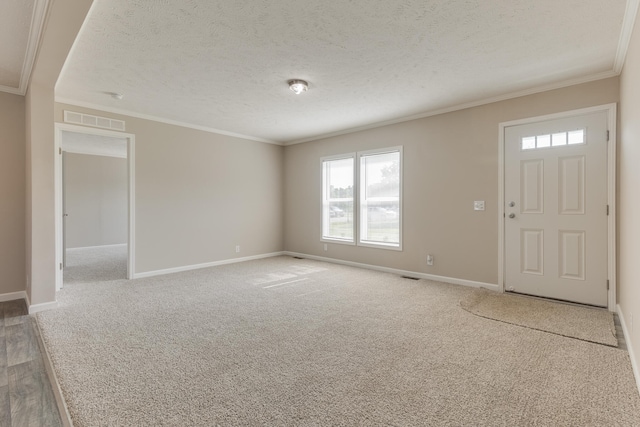 entrance foyer featuring carpet, a textured ceiling, and ornamental molding