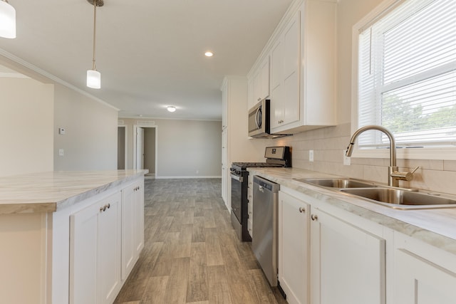 kitchen featuring decorative light fixtures, stainless steel appliances, white cabinetry, and sink