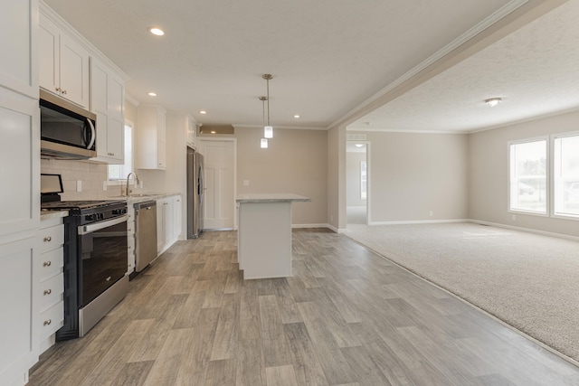 kitchen featuring light wood-type flooring, stainless steel appliances, pendant lighting, white cabinets, and a kitchen island