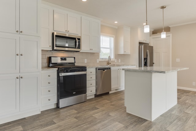 kitchen featuring white cabinetry, a kitchen island, ornamental molding, and appliances with stainless steel finishes