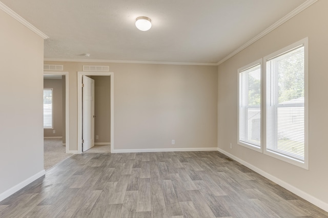 unfurnished room with light wood-type flooring, ornamental molding, and a wealth of natural light