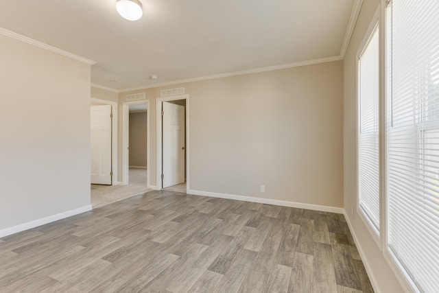 spare room with light wood-type flooring and ornamental molding