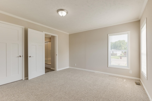 empty room featuring carpet, a textured ceiling, and ornamental molding